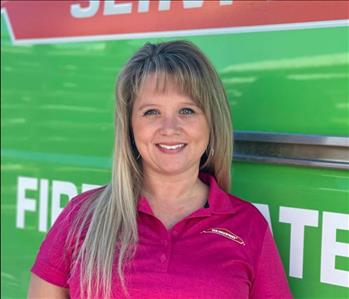 Woman standing in front of a green SERVPRO vehicle