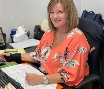 Woman in an orange shirt sitting at her desk